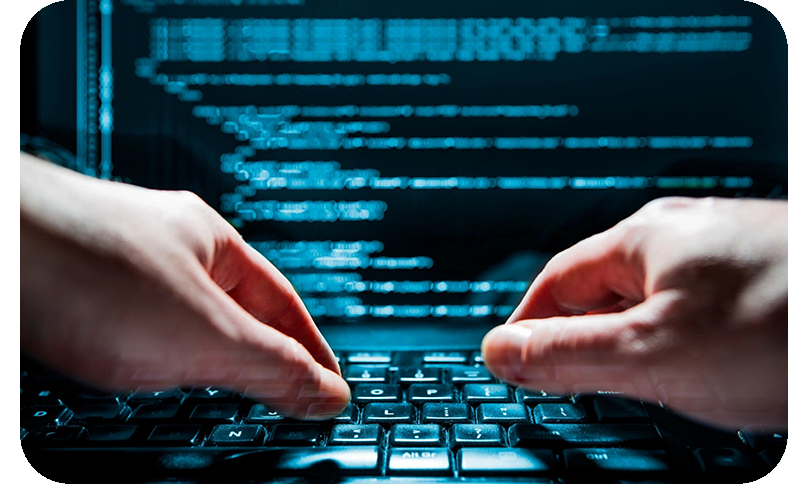 A person typing on a keyboard with a computer screen in the background.